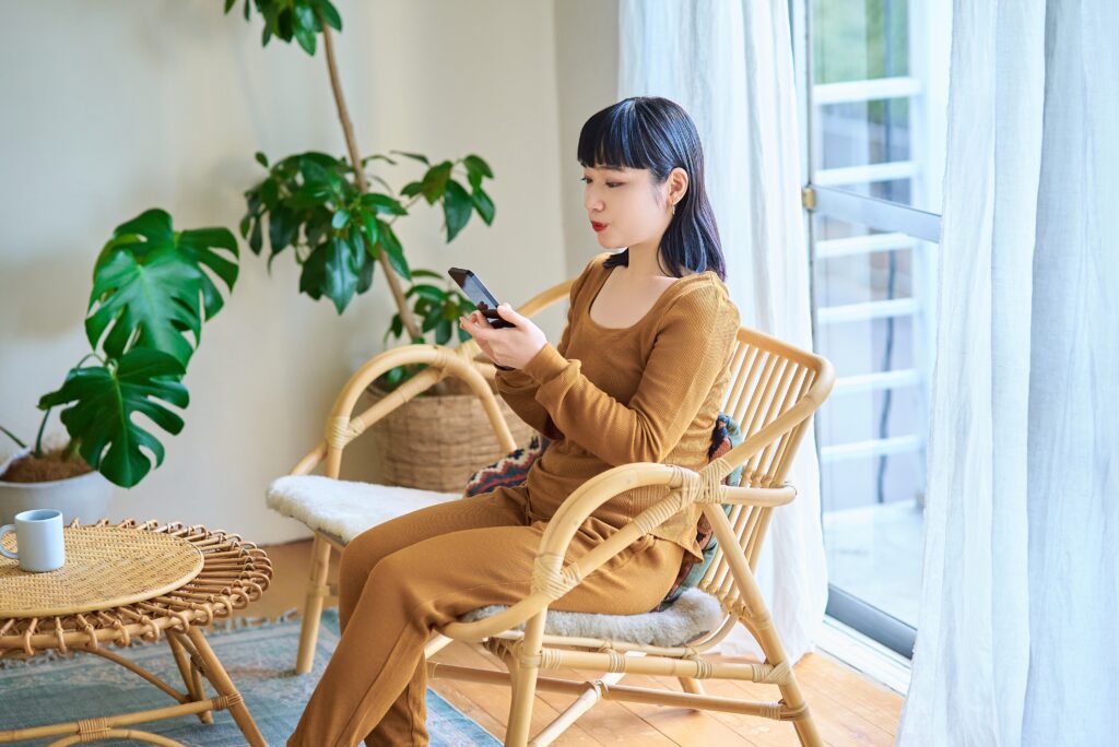 女性が椅子に座って、スマホを見ている様子